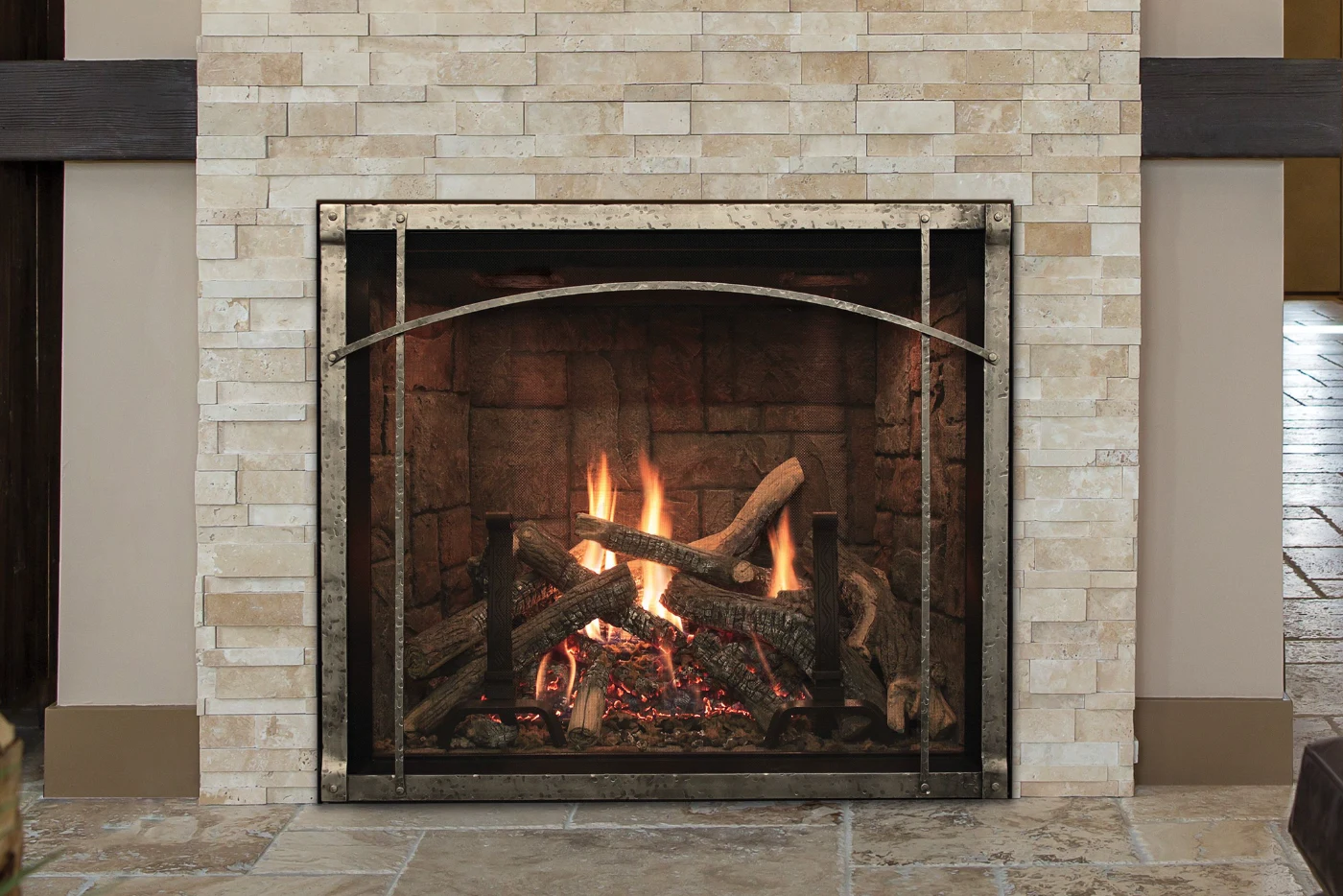 Cozy indoor stone fireplace with burning logs and a decorative metal fire screen