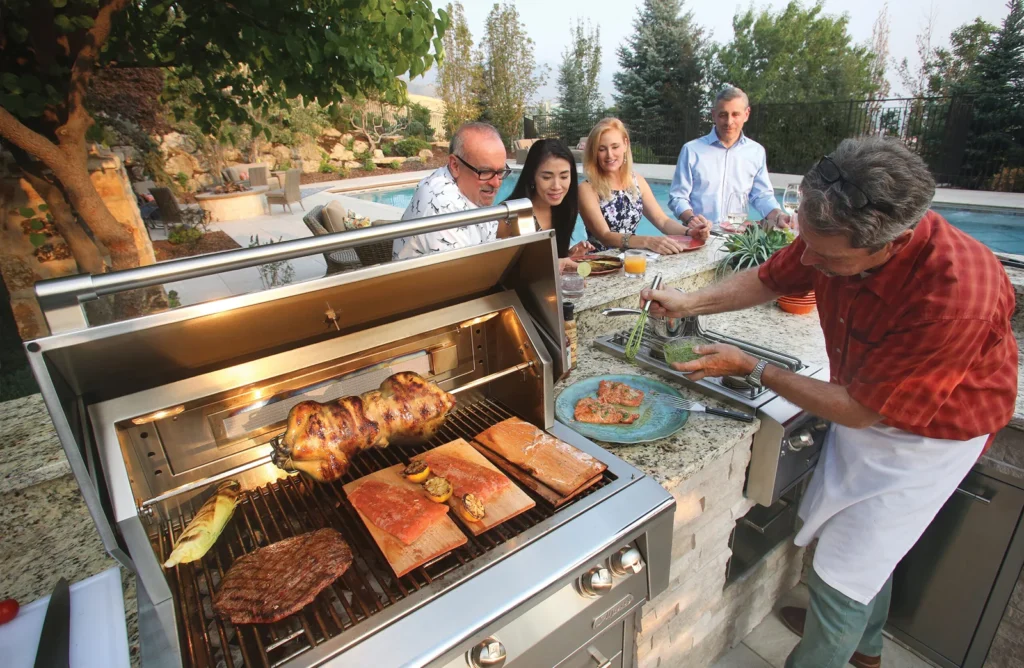 Man grilling salmon, chicken, and steak for guests at outdoor kitchen bar poolside