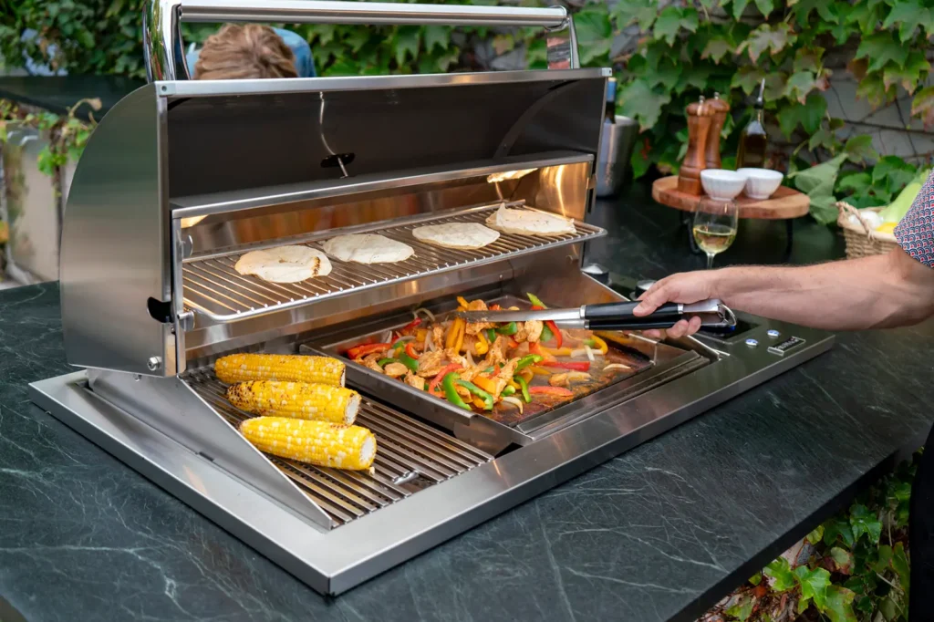 Outdoor grill with skewered vegetables, corn and pita bread cooking on stainless steel grates