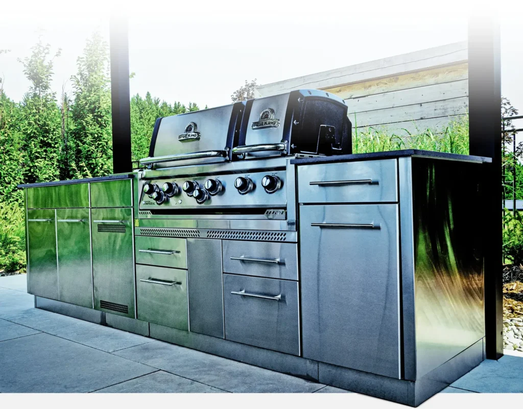 Stainless steel outdoor kitchen grill island with cabinet storage on a backyard patio